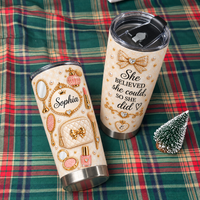 Two custom vanity design tumblers placed on a red and green plaid blanket next to a small holiday tree ornament.