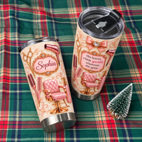 Two personalized hair stylist tumblers featuring rose gold salon tools and custom name on plaid blanket beside miniature