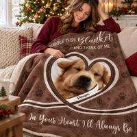 A woman sitting on a couch wrapped in a custom brown plush throw blanket designed for dog owners grieving pet loss.