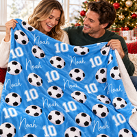 A couple holds up a custom blue soccer ball pattern blanket featuring the name Noah and number 10.