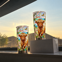 Two custom name tumbler cups with Highland cow design standing on windowsill with sunset sky and rooftop background.