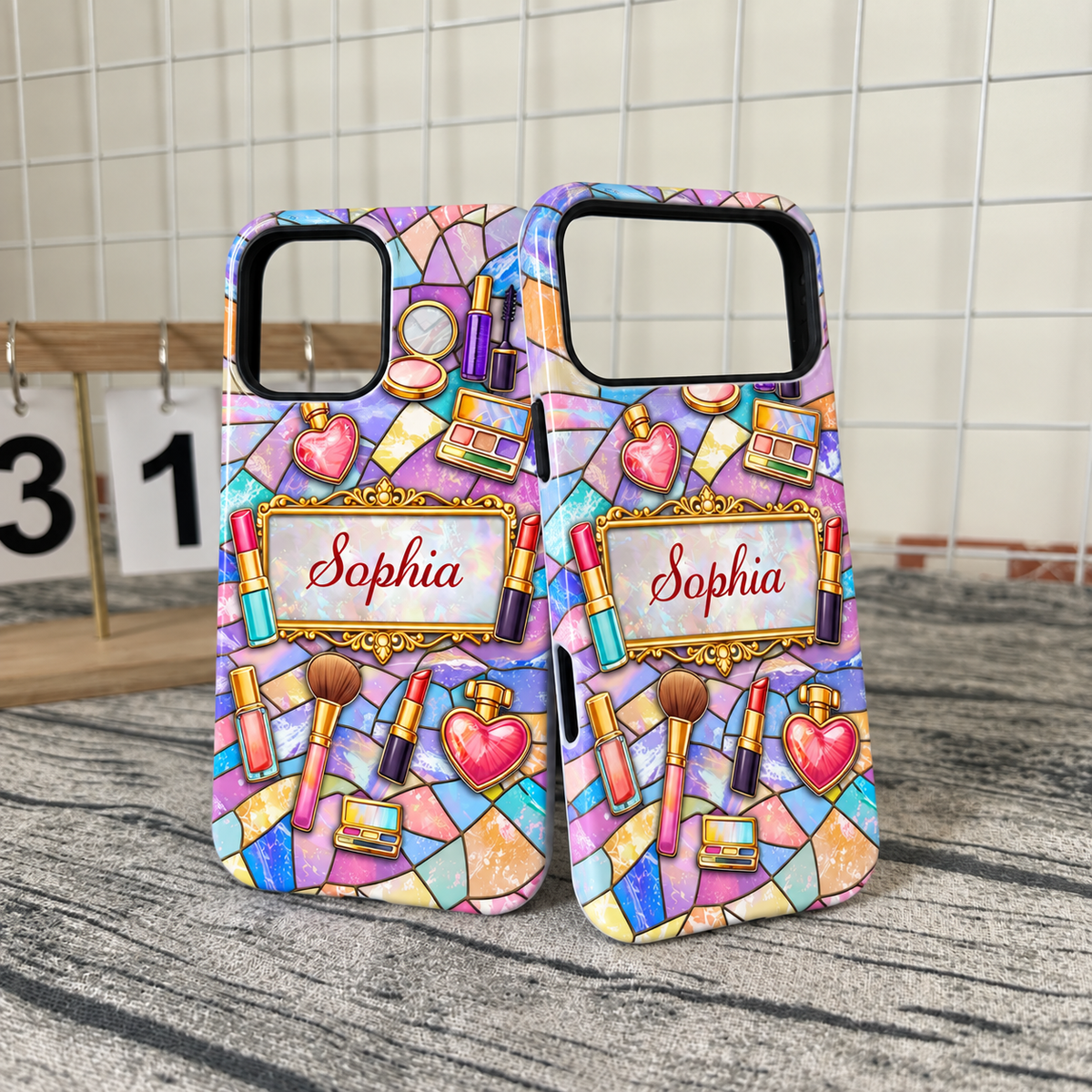 Two personalized makeup phone cases with stained glass mosaic design and name Sophia displayed together in front of grid