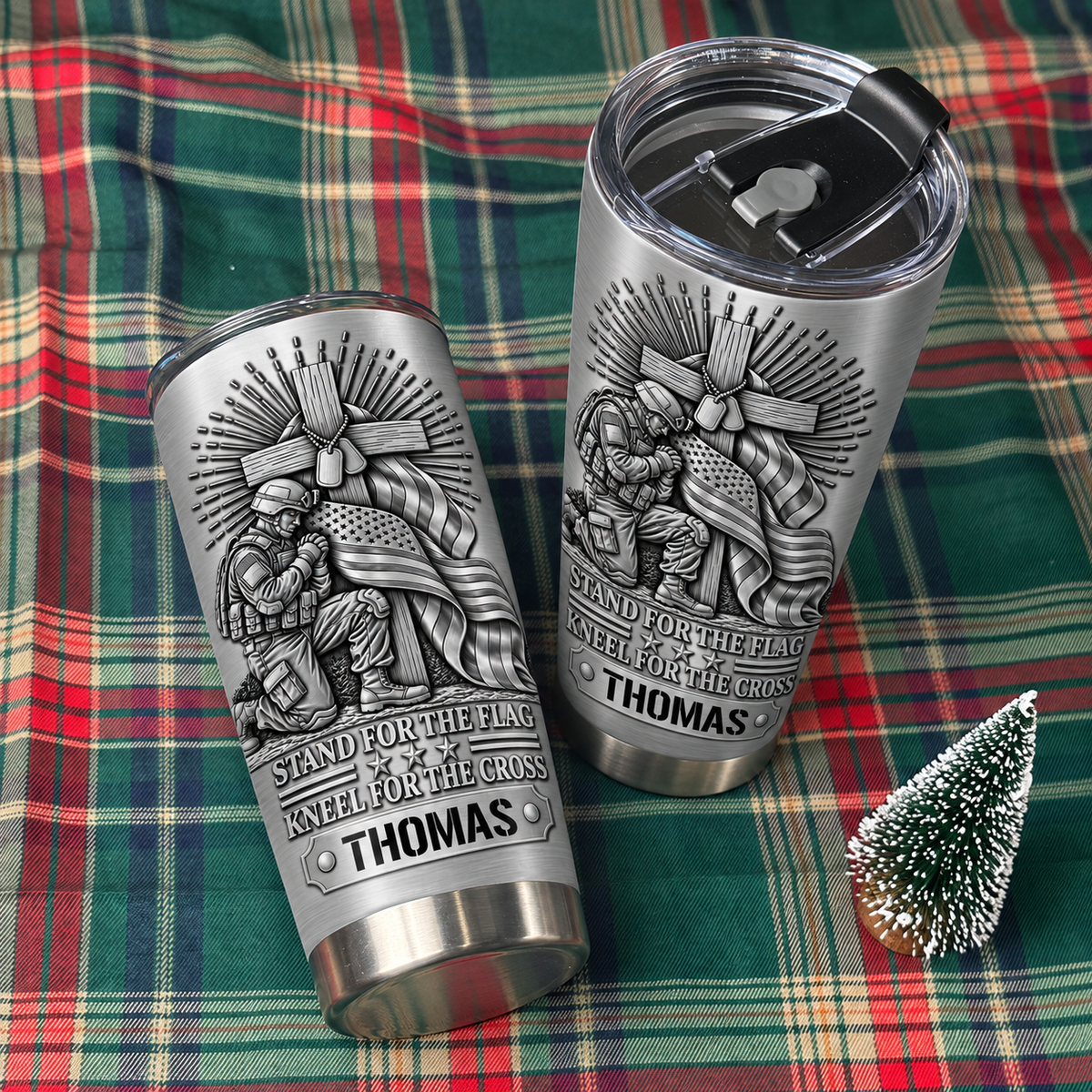 Two custom name tumblers displayed on a red and green plaid holiday blanket.