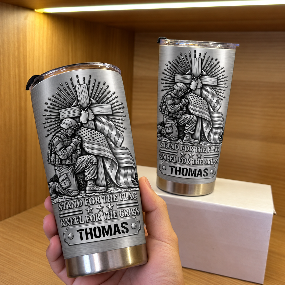 A hand holding a custom name tumbler with a second matching tumbler on a box.