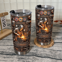 Two custom name welder tumblers displayed on wooden shelf with white grid wall behind.