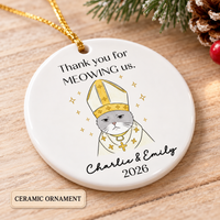 Personalized round ceramic cat wedding gift ornament resting on a wooden surface next to pinecones.