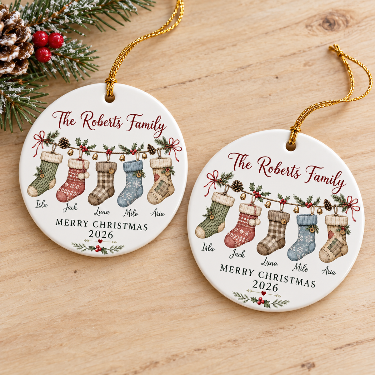 Two round ceramic family stocking ornaments displayed side by side on a wooden surface with pine needles.