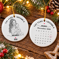 Front and back views of The Year I Became A Mama ceramic ornament resting on a rustic wooden surface.