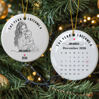 Two round ceramic ornaments featuring The Year I Became A Mama design hanging on a Christmas tree.