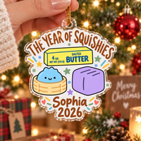 Hand holding clear acrylic squishy ornament with personalized name and 2026 text.