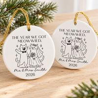 Two personalized cat wedding ornaments resting side by side on a wooden surface.