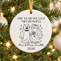 Cat wedding ornament in white ceramic hanging on a lit Christmas tree with a gold ribbon.