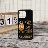 A black iPhone tough case with a gold lion and witty family message standing upright on a textured table near a calendar desk