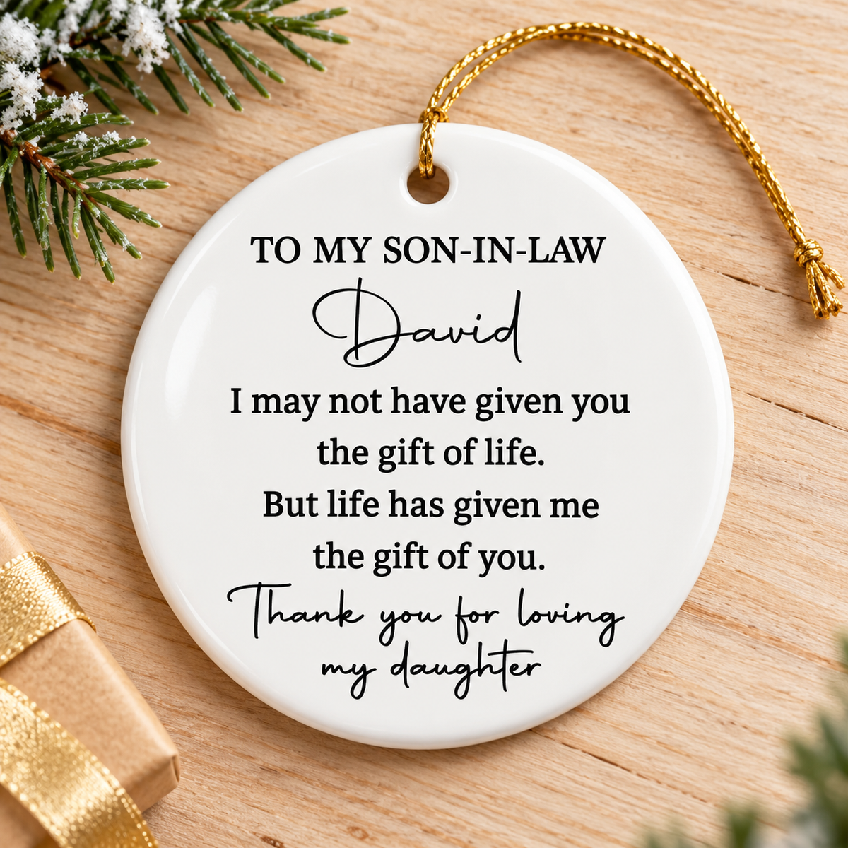 Personalized To My Son-In-Law ornament resting on a light wooden table next to a pine branch and gift.
