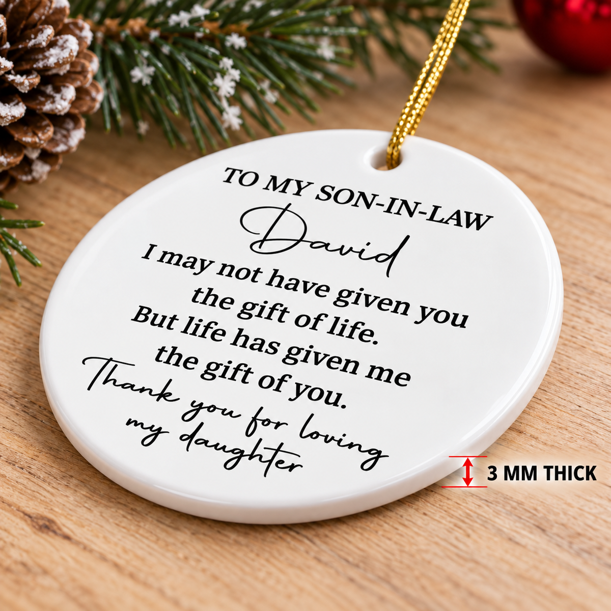 Ceramic ornament for son in law angled on wood surface with pinecones, showing 3mm thickness detail.