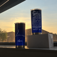 Two stainless steel tumbler cups with starry galaxy prints sit on a windowsill against a glowing sunset background.