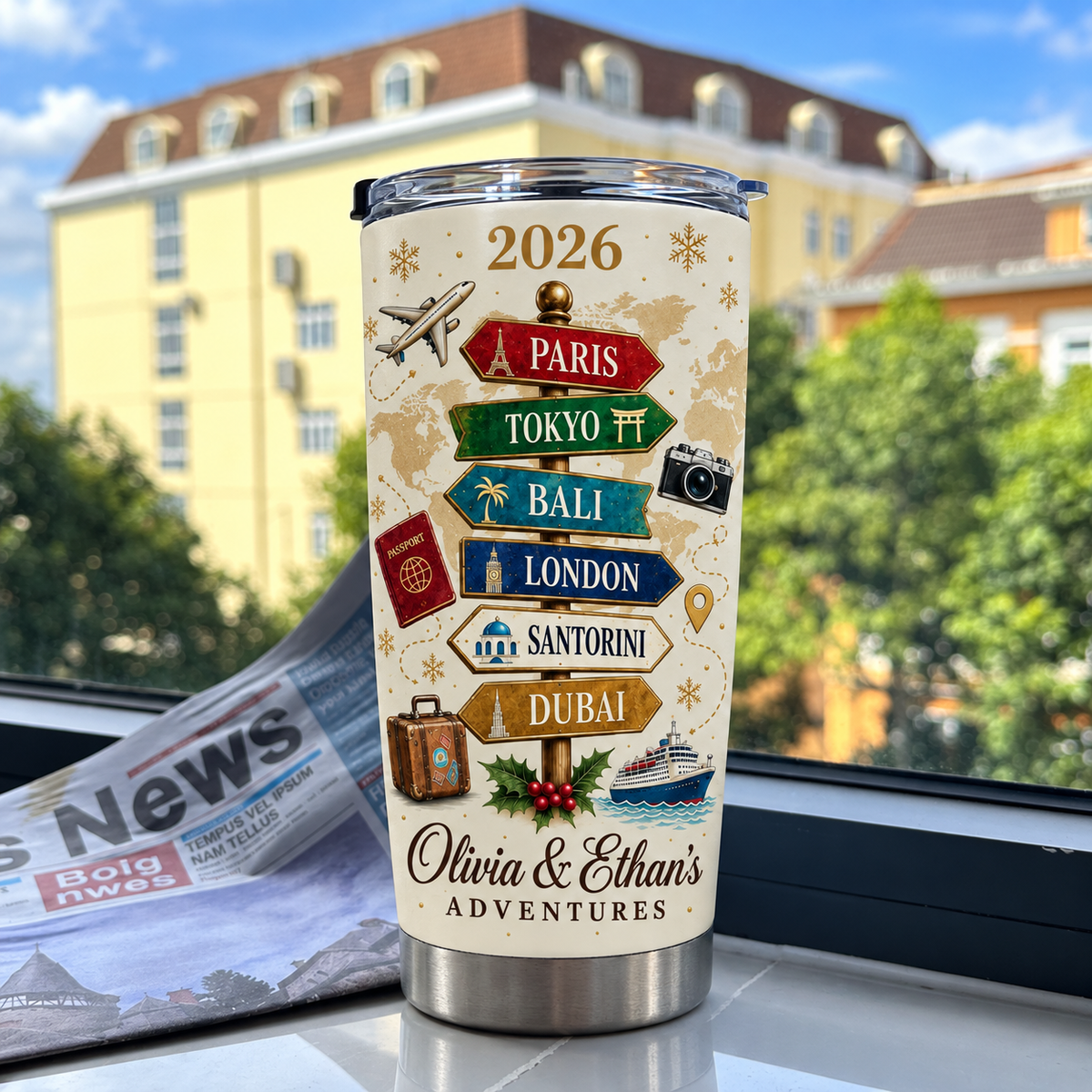 A personalized stainless steel travel cup with a vintage travel signpost design standing upright on a windowsill overlooking