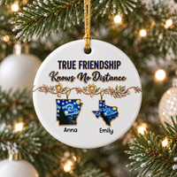 Round white ceramic long distance best friend gift ornament hanging on a snowy Christmas tree with twinkling fairy lights.