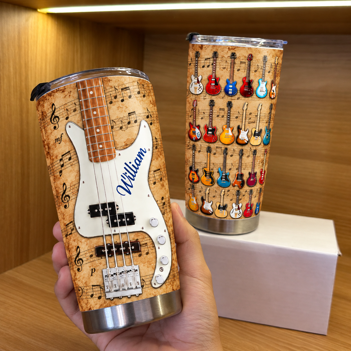 Hand holding a vintage guitar music sheet tumbler with blue custom name William next to a second tumbler on a white box.