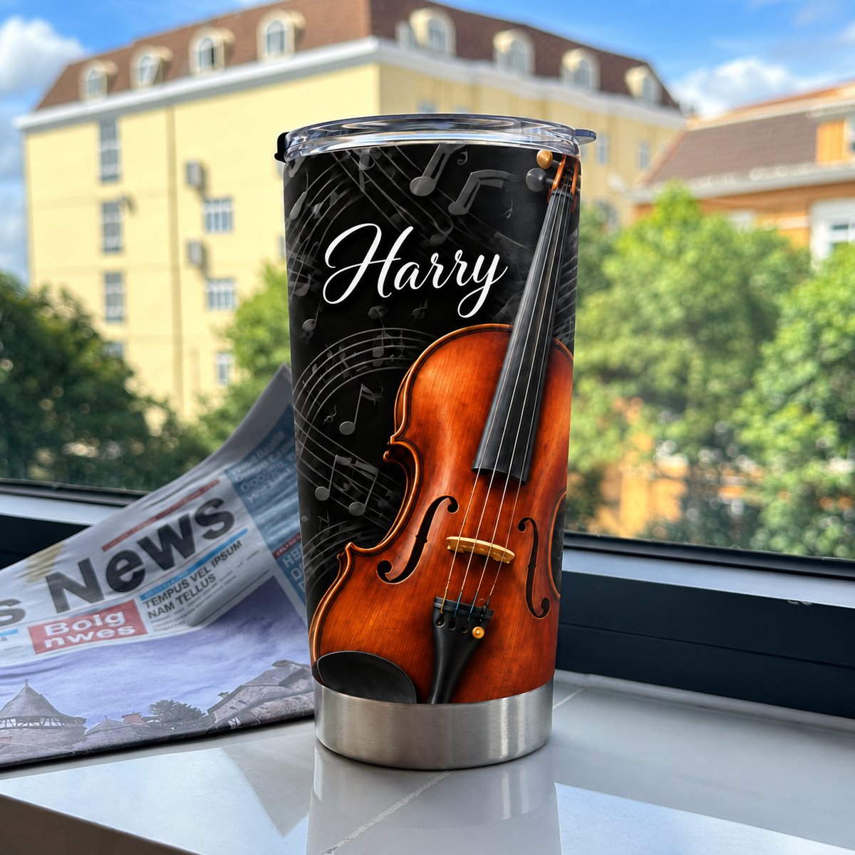 Personalized violin music tumbler standing upright on a white surface near a window with a newspaper backdrop.