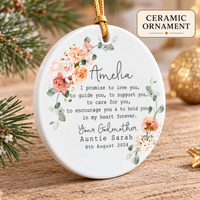 Round ceramic ornament with peach floral wreath resting on a wooden surface near pine needles.