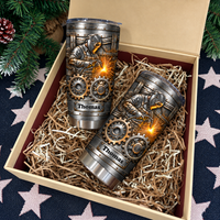 Top-down view of two custom stainless steel welder tumblers nestled inside a gift box with shredded paper.