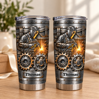 Two identical stainless steel welder tumblers with a steampunk gear graphic standing side-by-side on a wooden table.