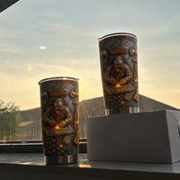 Two welder personalized tumblers with custom name standing against a hazy window and sky background.