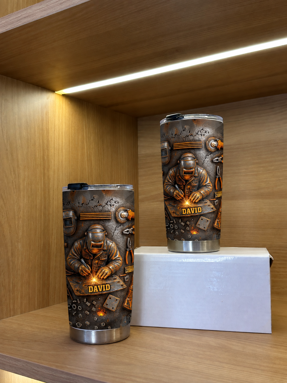 Two welder personalized tumblers with custom name on a wooden shelf with overhead lighting.