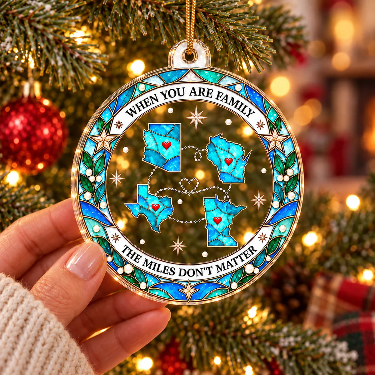 A hand holding a round clear acrylic Christmas ornament featuring connected state outlines and a quote.