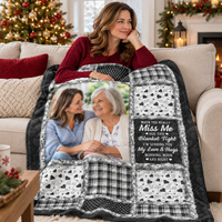 Woman relaxing on a couch with a hug this blanket tight quilt featuring black and white patchwork and family photos.