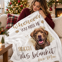 A woman sitting on a living room sofa holds up a soft custom dog name blanket near a Christmas tree.
