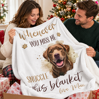 A smiling couple opening a box together and holding up a personalized pet loss sympathy blanket at Christmas.