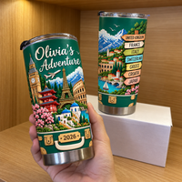 Hand holding the personalized adventure mug with world landmarks in front of a wooden storage box.