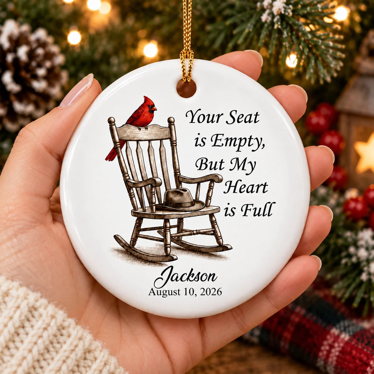 Hand holding a personalized bereavement gift ornament against a backdrop of glowing holiday lights.